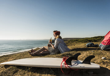 Junges Paar mit Surfbrett beim Camping am Meer - UUF08747