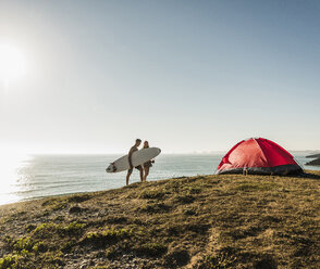 Junges Paar mit Surfbrett beim Camping am Meer - UUF08752