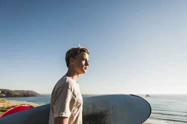 Jugendlicher mit Surfbrett und Blick auf das Meer - UUF08756