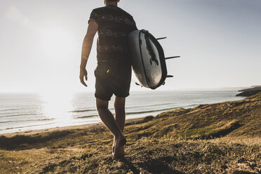 Rückenansicht eines Teenagers mit Surfbrett, der zum Meer läuft - UUF08760