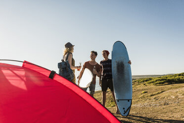 Drei Freunde mit Surfbrettern beim Zelten am Meer - UUF08762