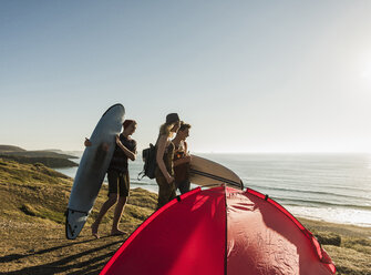 Drei Freunde mit Surfbrettern beim Zelten am Meer - UUF08763