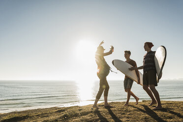 Drei Freunde mit Surfbrettern beim Zelten am Meer - UUF08765