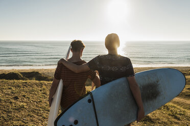 Rückenansicht von zwei besten Freunden mit Surfbrettern am Meer - UUF08766
