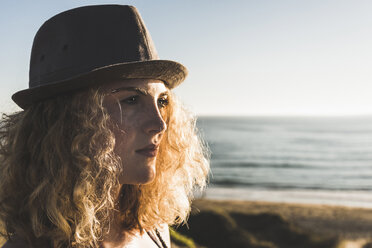 Portrait of blond teenage girl wearing hat on the beach at evening twilight - UUF08774