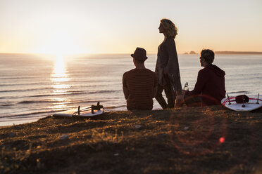 Drei Freunde genießen den Sonnenuntergang am Strand - UUF08807