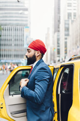 Indischer Geschäftsmann in Manhattan beim Einsteigen in ein gelbes Taxi - GIOF01531