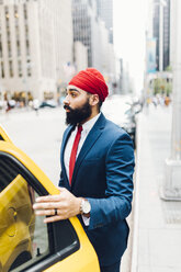 Indischer Geschäftsmann in Manhattan beim Einsteigen in ein gelbes Taxi - GIOF01534