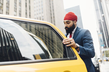 Indischer Geschäftsmann in Manhattan beim Einsteigen in ein gelbes Taxi - GIOF01536