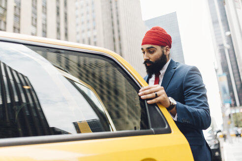 Indian businessman in Manhattan entering a yellow cab - GIOF01536