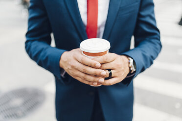 Geschäftsmann beim Spaziergang in der Stadt, mit einer Tasse Kaffee in der Hand - GIOF01552