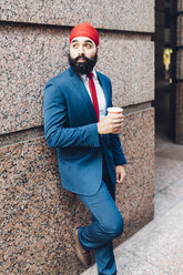 Indischer Geschäftsmann in Manhattan, der an der Wand lehnt und Kaffee trinkt - GIOF01561