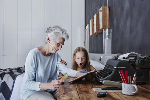 Grandmother and amazed granddaughter shopping online at home - RORF00314