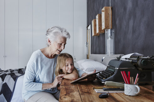 Großmutter und Enkelin betrachten Tablet zu Hause - RORF00318