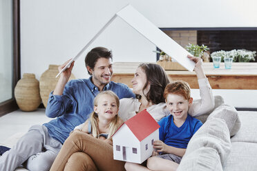 Happy family of four with house model in living room - RORF00337