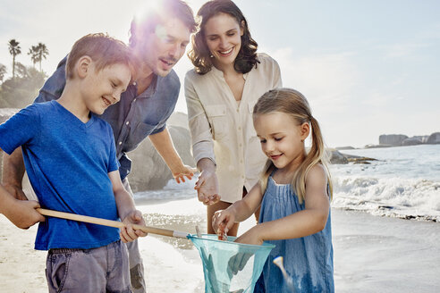 Glückliche Familie mit Tauchnetz am Strand - RORF00356