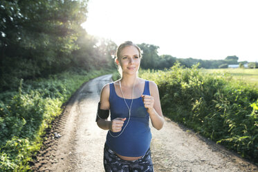 Schwangere Frau joggt auf einem Feldweg - HAPF00994