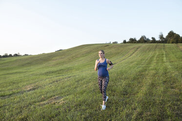 Schwangere Frau joggt im Feld - HAPF01006