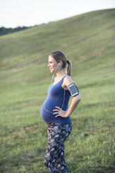 Schwangere Frau steht im Feld und macht eine Pause vom Joggen - HAPF01009