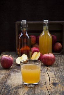 Flasche und Glas mit Apfelsaft, trüb und klar, rote Äpfel auf Holz - LVF05443