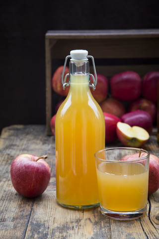 Flasche und Glas mit Apfelsaft, trüb und klar, rote Äpfel auf Holz, lizenzfreies Stockfoto