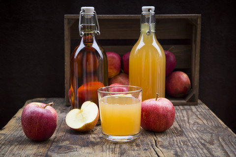 Bottle and glass of apple juice, cloudy and clear, red apples on wood stock photo