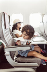 Two little girl flying on plane, playing with paperplane - MGOF02520