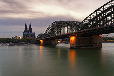 Deutschland, Köln, Blick auf den Kölner Dom mit der Hohenzollernbrücke im Vordergrund in der Abenddämmerung - GFF00813
