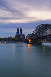 Deutschland, Köln, Blick auf den Kölner Dom mit der Hohenzollernbrücke im Vordergrund in der Abenddämmerung - GFF00814