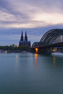 Deutschland, Köln, Blick auf den Kölner Dom mit der Hohenzollernbrücke im Vordergrund in der Abenddämmerung - GFF00814