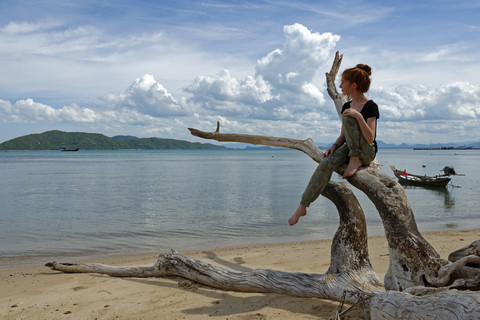 Thailand, Koh Samui, Jugendliches Mädchen sitzt auf abgestorbenen Wurzeln am Taling Ngam Strand, lizenzfreies Stockfoto