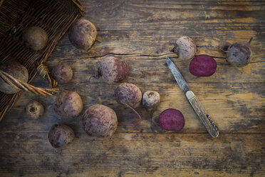 Ganze und geschnittene Rote Bete und ein Taschenmesser auf dunklem Holz - LVF05472