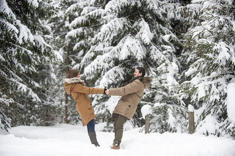 Glückliches Paar beim Spaziergang im Winterwald, lizenzfreies Stockfoto