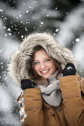 Young woman wearing fur hood in snow fall, portrait - HHF05446