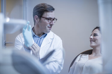 Dentist preparing treatment putting on surgical gloves - ZEF10610