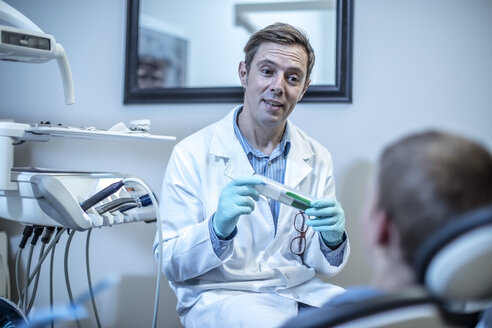 Zahnarzt mit Zahnbürste im Gespräch mit einem Jungen in einer Zahnarztpraxis - ZEF10635