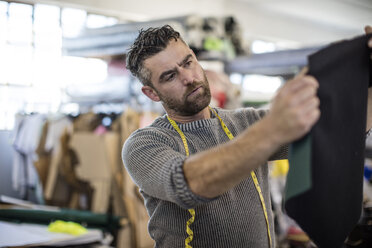 Tailor looking at clothing sample in workshop - ZEF10655