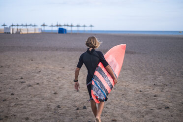 Spain, Tenerife, boy carrying surfboard on the beach - SIPF00947
