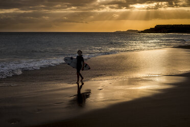 Spanien, Teneriffa, Junge mit Surfbrett am Strand bei Sonnenuntergang - SIPF00950