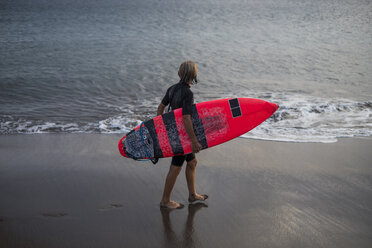 Spain, Tenerife, boy carrying surfboard at the sea - SIPF00951