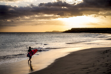 Spanien, Teneriffa, Junge mit Surfbrett am Strand bei Sonnenuntergang - SIPF00952