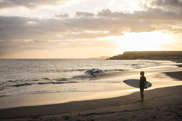 Spanien, Teneriffa, Junge mit Surfbrett am Strand bei Sonnenuntergang - SIPF00953