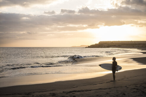 Spanien, Teneriffa, Junge mit Surfbrett am Strand bei Sonnenuntergang - SIPF00953