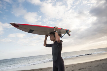 Spanien, Teneriffa, Junge mit Surfbrett am Strand - SIPF00955