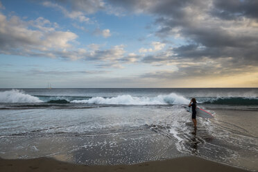 Spain, Tenerife, boy carrying surfboard on the beach at sunset - SIPF00956