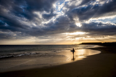 Spanien, Teneriffa, Junge mit Surfbrett am Strand bei Sonnenuntergang - SIPF00957
