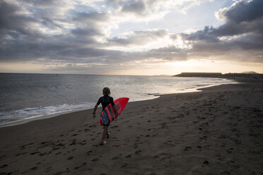 Spanien, Teneriffa, Junge mit Surfbrett am Strand bei Sonnenuntergang - SIPF00958