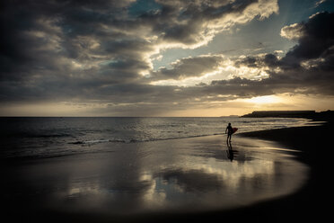 Spain, Tenerife, boy carrying surfboard on the beach at sunset - SIPF00960