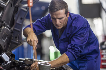 Automechaniker in einer Werkstatt bei der Reparatur eines Autos - ZEF10707