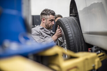 Car mechanic in a workshop changing tire - ZEF10716